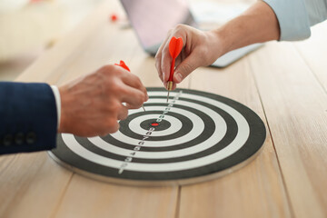 Men with darts aiming at dartboard indoors, closeup