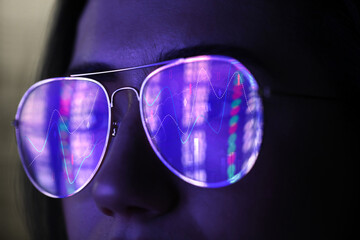 Stock exchange. Trader analyzing data, closeup. Graphs reflecting in her eyeglasses