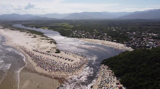 4K drone pullback of Guarda do Emba&uacute; beach with paddlers, tourists and forested mountains &ndash; Brazil