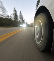 A car is speeding down a road with a bright light shining on the tire