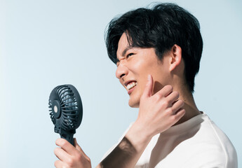 汗をかき、ハンディファンを持つ日本人男性