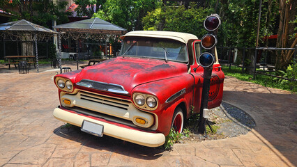 Red vintage truck parked on road beside traffic light with tree and house or home background. Retro or classic vehicle and old car style for show.