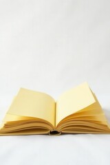 Golden yellow hardcover book open on stark white background, textbook, blank pages