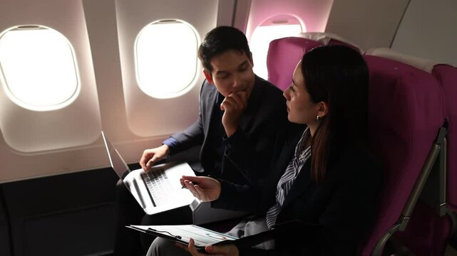 businessman and his secretary discuss sales paper while traveling by plane to sign a contract with another company, during the business trop of the two businessmen they double-checked to be sure