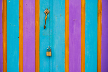 Puerta de madera pintada en colores vibrantes con cerradura y pasador – diseño colorido y simétrico ideal para fondos creativos o conceptos de seguridad