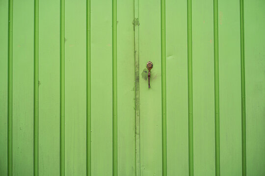 Puerta met&aacute;lica verde con dise&ntilde;o de l&iacute;neas verticales y cerradura antigua - foto de stock 