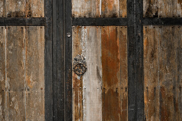 Puerta de madera envejecida con marco metálico y llamador antiguo de hierro oxidado - foto de stock 