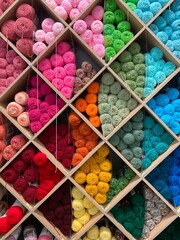 Colorful balls of yarn organized in cubbies on wall