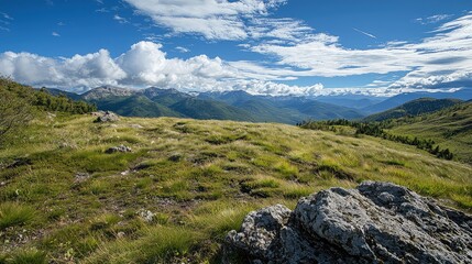 Green Hills Landscape with Distant Mountains Under a partly Cloudy Blue Sky with Foreground Rock Features on a Sunny
