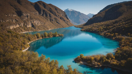 Vibrant turquoise lake nestled between towering mountains under a clear, sunny sky.