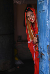 Portrait of Indian poor rural woman from village in colorful traditional saree standing outside...