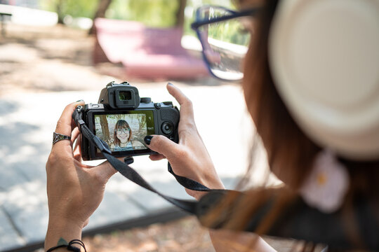 Photographer checking photos on professional digital camera screen while wearing headphones in a park