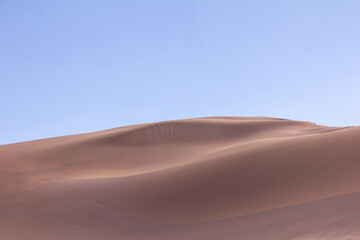 Dunas suaves de arena rojiza bajo cielo despejado en el desierto de Atacama, paisaje minimalista y natural
