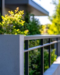 Fototapeta premium Modern Gray Concrete Fence with Dark Gray Metal Railings and Lush Green Foliage
