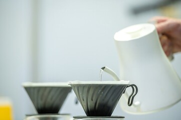 Barista pouring hot water over coffee grounds in a filter.