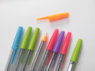 Assorted Colorful Ballpoint Pens with Orange Cap Removed on White Background