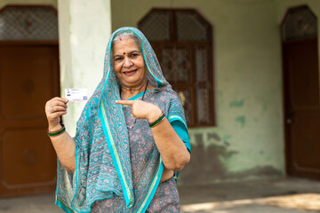 Portrait of Indian old woman showing showing unique identity card at village. Indian senior rural woman showing Aadhar card at home. Concept of rural woman empowerment in india.