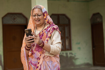 Indian happy old rural woman talking on phone at village