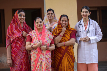 Concept of Rural Health in India. Indian rural women  standing while looking at the camera with young female doctor in rural courtyard shelter village, Rural India healthcare 