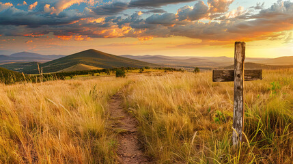 Golden prairie landscape with wooden trail sign pointing towards mountains under dramatic sunset. Concept of adventure, exploration and untouched natural beauty in wilderness.