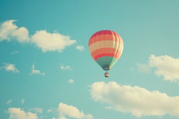 Obraz premium Colorful hot air balloon rises gently into the clear blue sky on a bright sunny day, Colorful hot air balloon ascending in clear blue sky with fluffy clouds