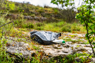 Garbage bag with remains of human garbage thrown in the field polluting nature.