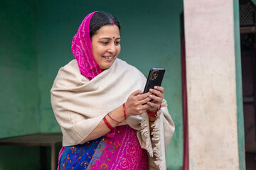 Indian rural woman using phone in village. Concept pf rural connected in India and mobile banking,...