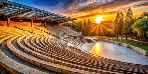 A modern amphitheater is bathed in warm light as the sun sets behind it, architecture, theater