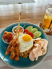 Indonesian brunch meal of fried rice with egg and chicken satay skewers