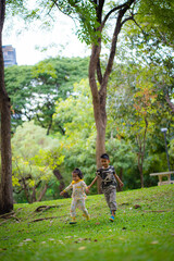 Fototapeta premium Adorable kid boy and girl enjoy run on greeen meadow grass city park