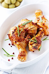 Spicy Chicken Drumsticks with fresh herbs. White wooden background