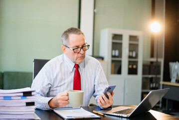 Senior businessman rips paperwork in rage at office desk. Workplace stress, anger, chaos, and...
