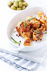 Spicy Chicken Drumsticks with fresh herbs. White wooden background