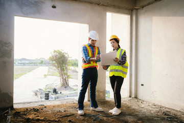 Engineers and architects collaborate at a construction site, wearing safety gear, examining...