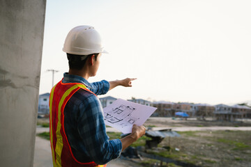 Engineers and architects collaborate at a construction site, wearing safety gear, examining...