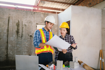Engineers and contractors inspect construction plans indoors, using technology and equipment to...