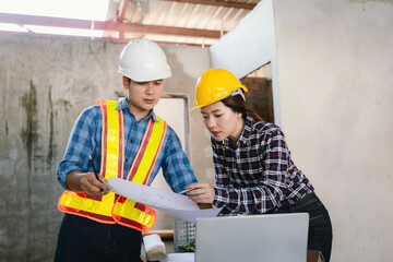 Engineers and contractors inspect construction plans indoors, using technology and equipment to...