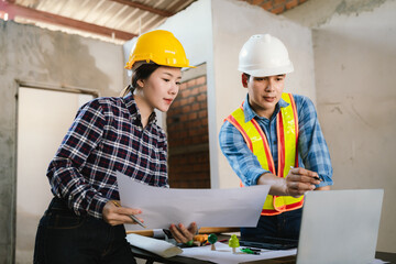 Engineers and contractors inspect construction plans indoors, using technology and equipment to...
