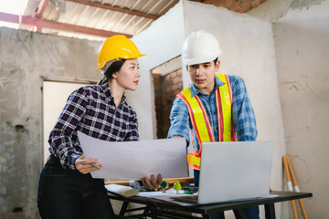 Engineers and contractors inspect construction plans indoors, using technology and equipment to...