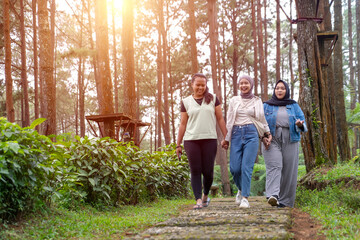 Fototapeta premium Three Young Asian Women Walking Together and Smiling in Forest Path