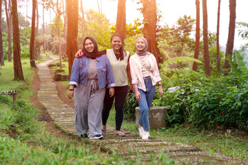 Fototapeta premium Three Young Asian Women Walking Together and Smiling in Forest Path