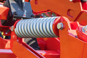 Naklejka premium Steel silver spring as part of red heavy agricultural, industrial machine. Technology