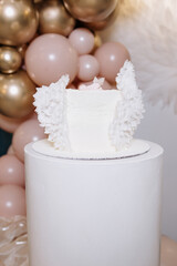 White cake for celebrating a child's baptism. Sweet cake with white wings. Photo zone for a child's...