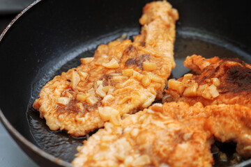Chicken breast pieces frying in garlic dressing on a skillet, capturing a flavorful and healthy cooking process
