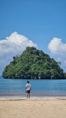Lonely Young Man Gazing at Distant Island from Empty Sunny Beach