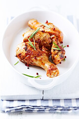 Spicy Chicken Drumsticks with fresh herbs. White wooden background