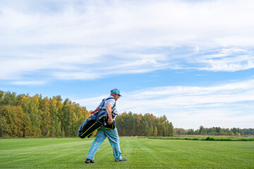 Obraz premium A man is leisurely walking on a beautiful golf course while carrying his golf equipment with him