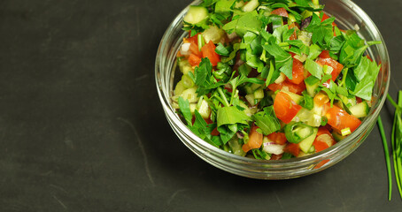 Salad from fresh cucumbers and tomatoes in a glass bowl