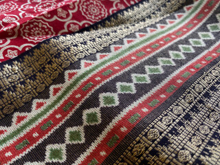 Angle view of cotton fabric displaying bold geometric stripes in black, white, and red, with woven...