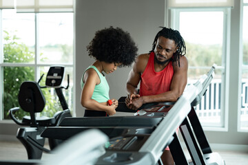 African American kid girl exercise on a exercise treadmill with trainer at gym